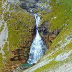 Cascada cayendo por una pared de roca del valle de Ordesa entre vegetación