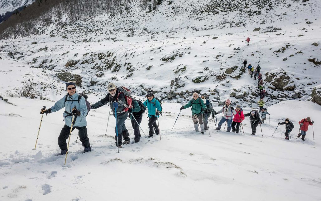 Grupo de personas caminando con raquetas por la nieve