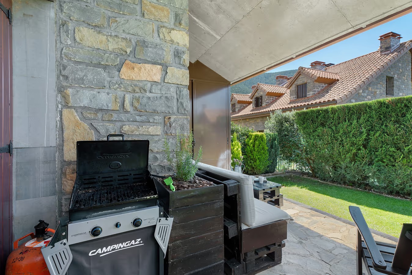 Barbacoa bajo el porche, con el jardín al fondo