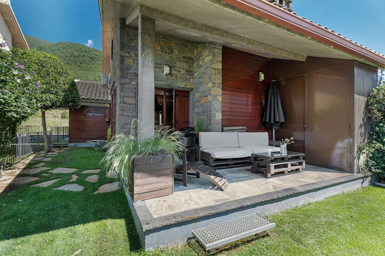 Porche de Casa Biescas con sofás de palés y el jardín