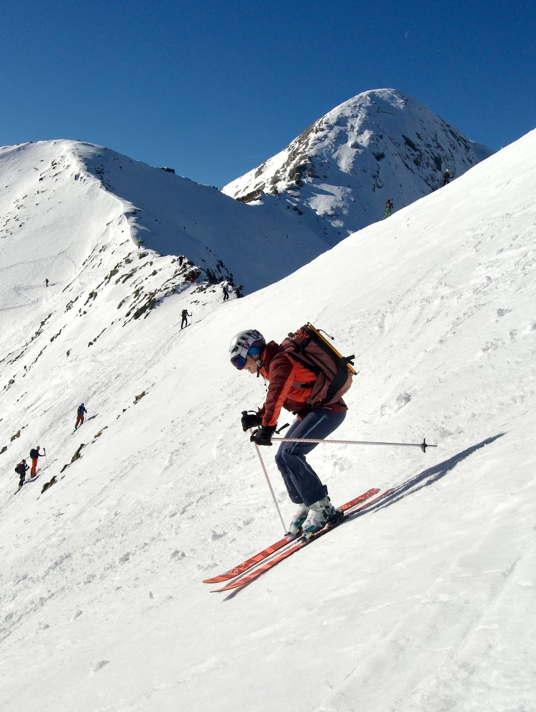 Esquiador descendiendo una ladera de Formigal mientras otros suben hacia la cima